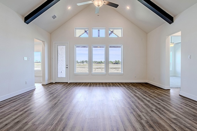 unfurnished living room with dark wood-type flooring, a wealth of natural light, ceiling fan, and beamed ceiling