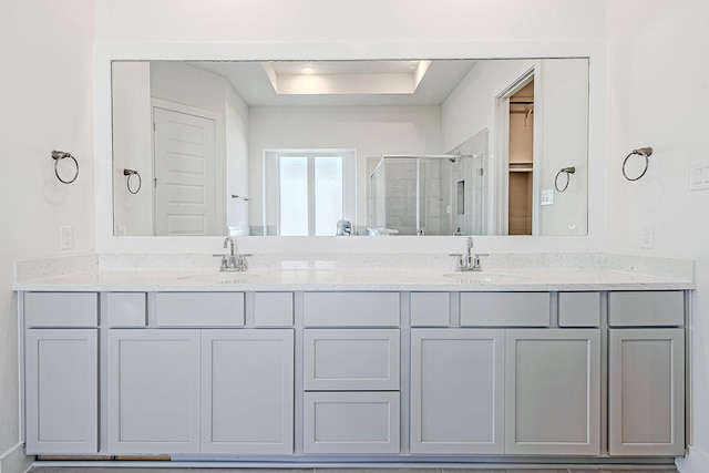 bathroom featuring a shower with shower door and vanity