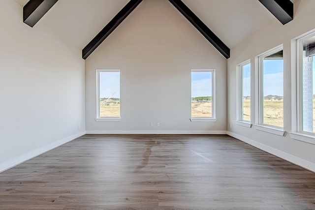 empty room featuring beam ceiling, hardwood / wood-style floors, and high vaulted ceiling