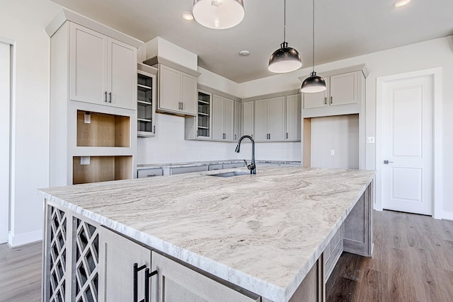 kitchen featuring hanging light fixtures, a kitchen island with sink, sink, and wood-type flooring