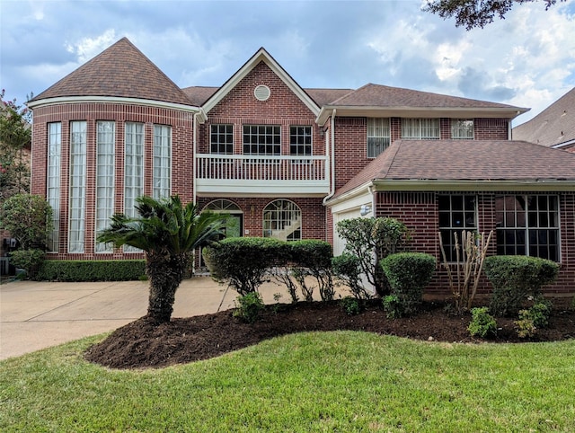 view of front facade featuring brick siding, concrete driveway, an attached garage, a front yard, and a balcony