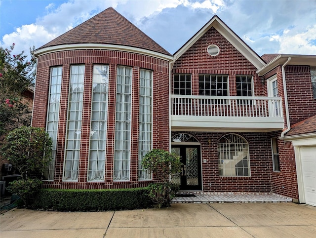 view of front of home with a garage, brick siding, a balcony, and roof with shingles