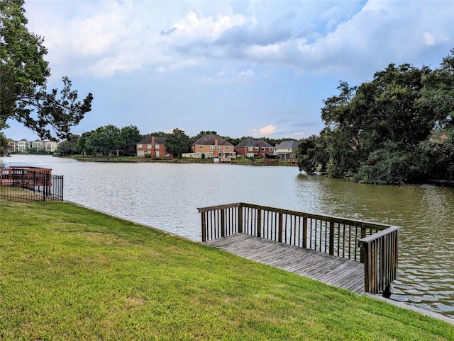 view of dock with a water view, a residential view, and a yard