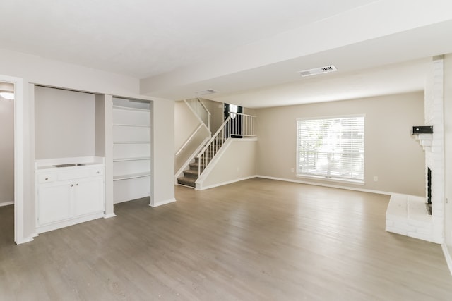 unfurnished living room with hardwood / wood-style floors and a brick fireplace