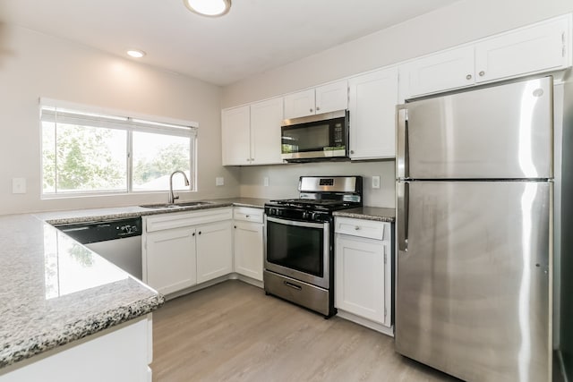 kitchen featuring appliances with stainless steel finishes, light hardwood / wood-style flooring, sink, and white cabinets