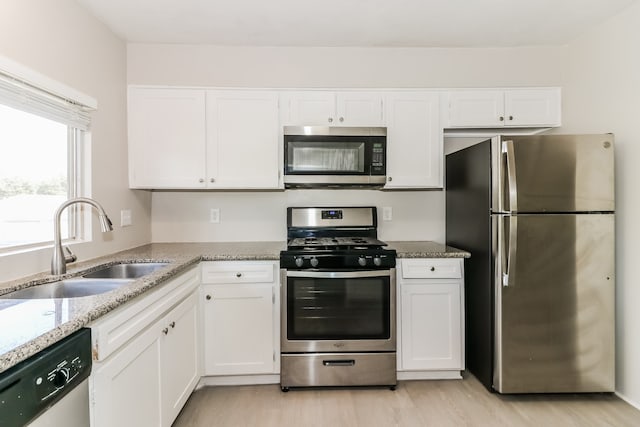 kitchen featuring light wood-type flooring, sink, stainless steel appliances, and white cabinets