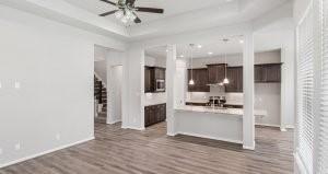 kitchen with a tray ceiling, wood-type flooring, ceiling fan, and dark brown cabinetry