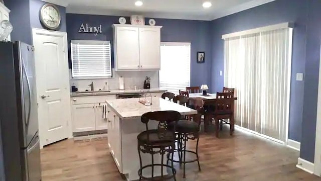 kitchen featuring a center island, white cabinetry, sink, stainless steel fridge, and wood-type flooring