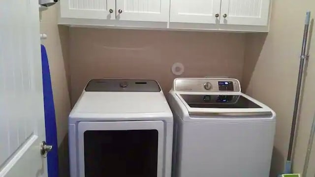 washroom with washing machine and dryer and cabinets