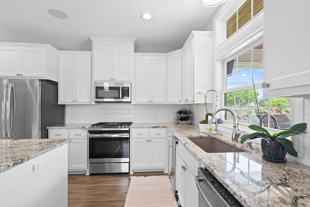 kitchen featuring backsplash, stainless steel appliances, white cabinetry, sink, and dark wood-type flooring