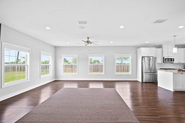 unfurnished living room with dark wood-type flooring, ceiling fan, and plenty of natural light