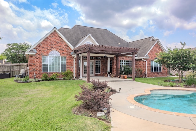 rear view of property featuring a yard, ceiling fan, a fenced in pool, and a patio