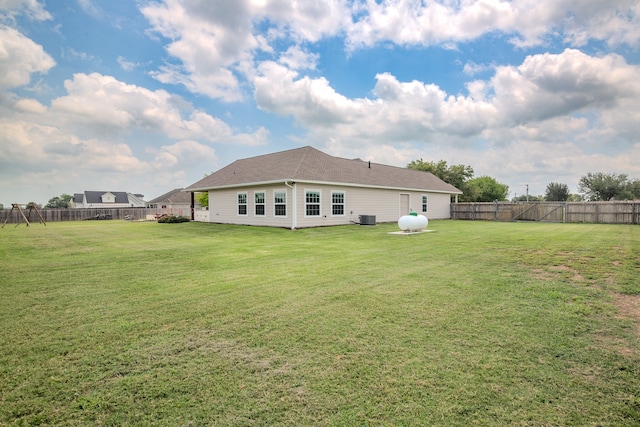 rear view of house featuring a lawn and central AC unit