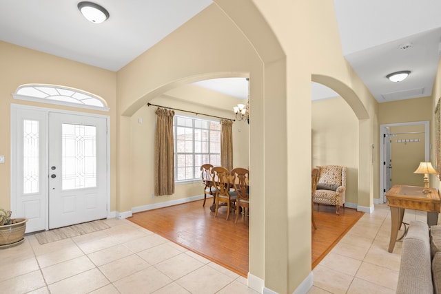 tiled entryway featuring a notable chandelier