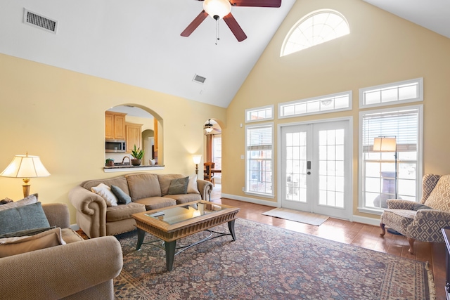 living room with a wealth of natural light, ceiling fan, hardwood / wood-style floors, and high vaulted ceiling