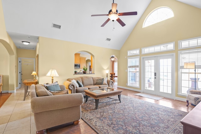 living room with high vaulted ceiling, ceiling fan, light tile patterned floors, and a healthy amount of sunlight