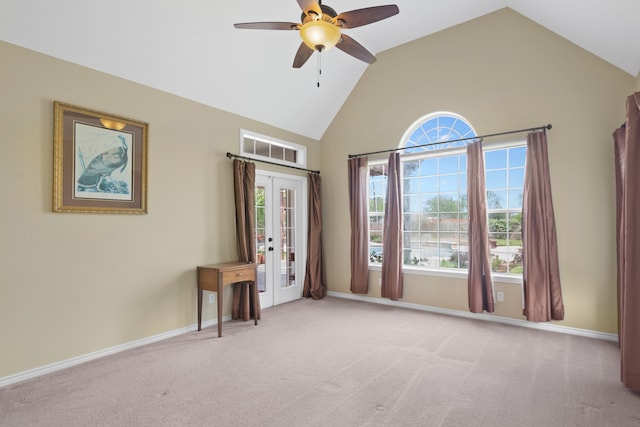 carpeted empty room featuring ceiling fan, high vaulted ceiling, and french doors