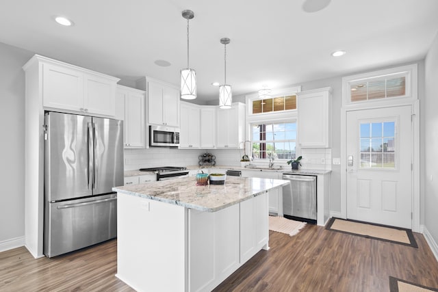 kitchen featuring a center island, appliances with stainless steel finishes, white cabinetry, dark hardwood / wood-style floors, and decorative backsplash