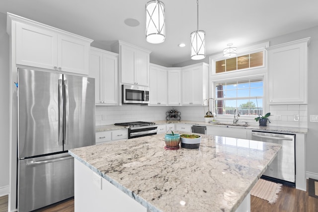 kitchen with dark hardwood / wood-style flooring, backsplash, appliances with stainless steel finishes, a center island, and white cabinetry