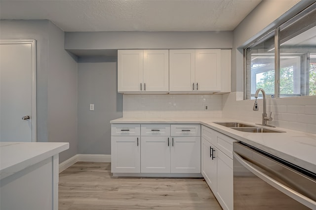 kitchen featuring dishwasher, light hardwood / wood-style flooring, backsplash, and white cabinets