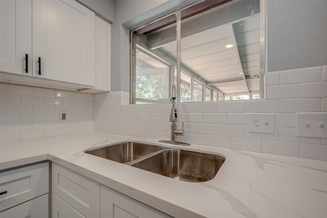 kitchen featuring white cabinets, vaulted ceiling, tasteful backsplash, and light stone countertops