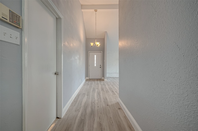 hallway featuring light wood-type flooring and a chandelier