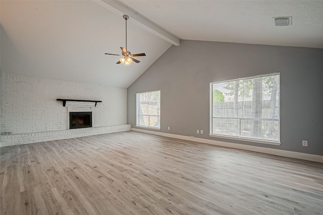 unfurnished living room with a fireplace, light hardwood / wood-style flooring, ceiling fan, brick wall, and beam ceiling