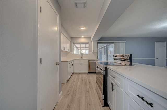 kitchen featuring light wood-type flooring, white cabinets, stainless steel appliances, and sink