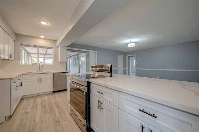 kitchen featuring white cabinets, appliances with stainless steel finishes, light hardwood / wood-style floors, sink, and decorative backsplash