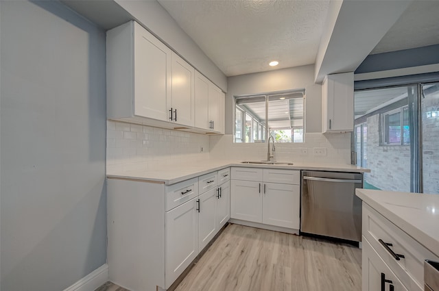 kitchen with white cabinetry, backsplash, dishwasher, sink, and light hardwood / wood-style floors