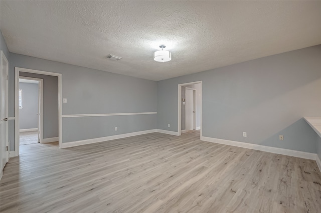 empty room featuring a textured ceiling and light hardwood / wood-style flooring