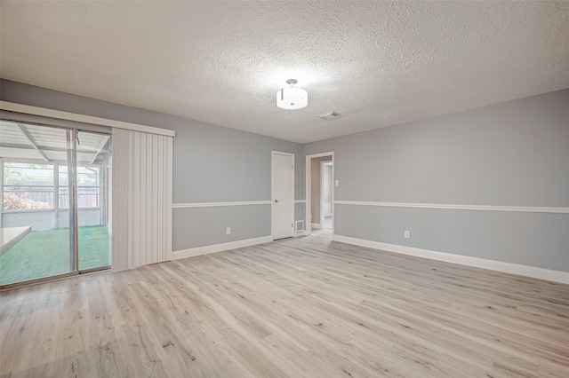 empty room with a textured ceiling and light hardwood / wood-style flooring