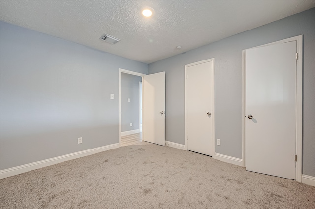 unfurnished bedroom featuring light carpet and a textured ceiling