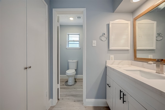 bathroom featuring wood-type flooring, toilet, and vanity