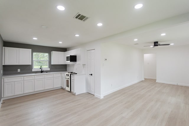 kitchen featuring white range with gas stovetop, light wood-type flooring, white cabinetry, sink, and ceiling fan