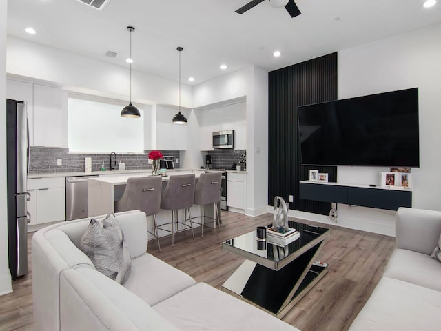 living room featuring ceiling fan, light hardwood / wood-style flooring, and sink