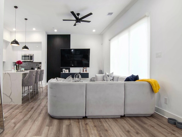 living room with light wood-type flooring and ceiling fan