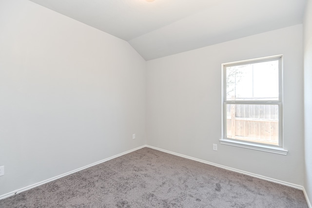 carpeted empty room with lofted ceiling and a healthy amount of sunlight