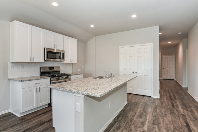 kitchen with stainless steel appliances, dark hardwood / wood-style flooring, white cabinetry, sink, and a kitchen island with sink