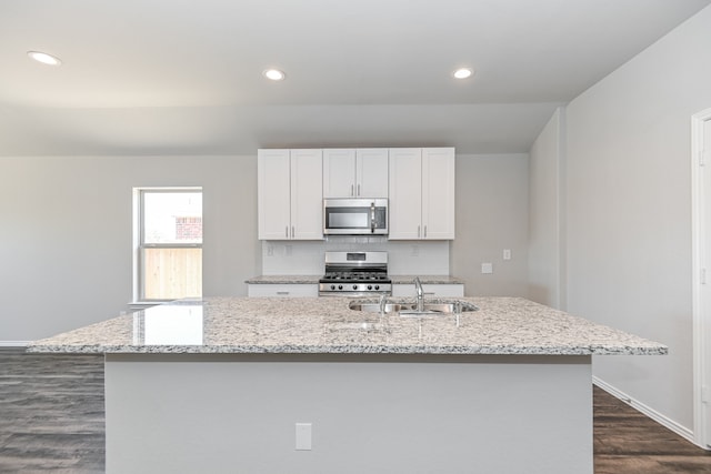 kitchen with dark hardwood / wood-style flooring, backsplash, a kitchen island with sink, stainless steel appliances, and sink