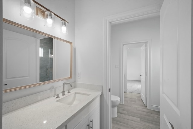 bathroom featuring vanity, toilet, wood-type flooring, and tiled shower