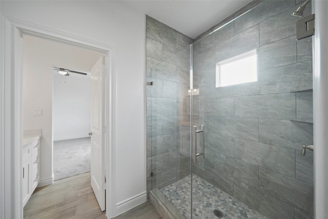 bathroom featuring vanity, hardwood / wood-style flooring, walk in shower, and ceiling fan