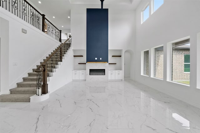 unfurnished living room featuring a high ceiling, light tile patterned floors, and a high end fireplace