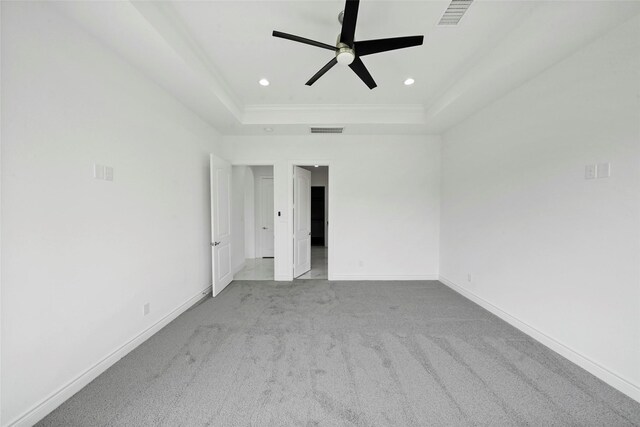 carpeted spare room featuring a raised ceiling and ceiling fan