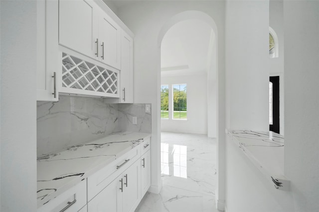 kitchen featuring light stone countertops, light tile patterned floors, and white cabinetry