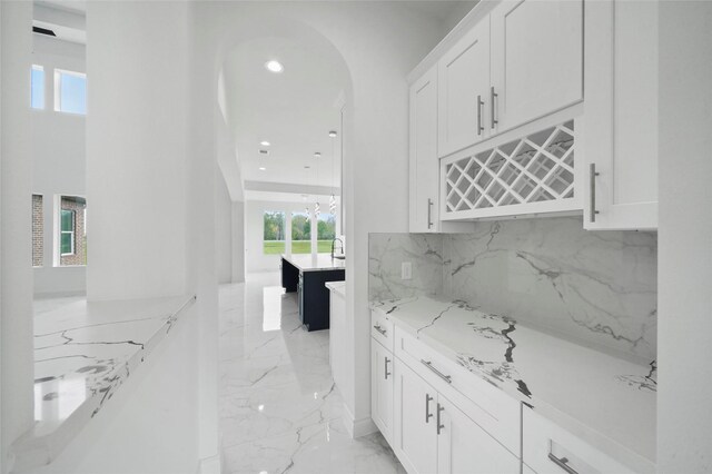 kitchen with light stone countertops, white cabinetry, and light tile patterned flooring