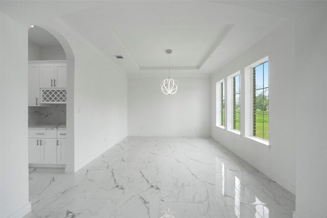 unfurnished dining area with a tray ceiling and light tile patterned floors