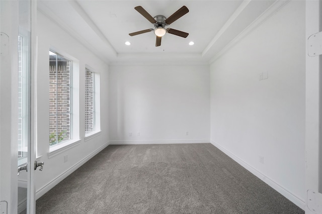 spare room with a tray ceiling, carpet floors, and ceiling fan