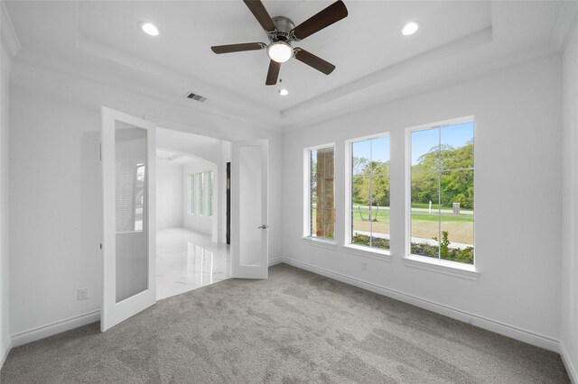 unfurnished bedroom with carpet flooring, multiple windows, and a tray ceiling