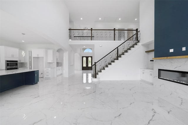 unfurnished living room with a fireplace, a towering ceiling, and light tile patterned floors